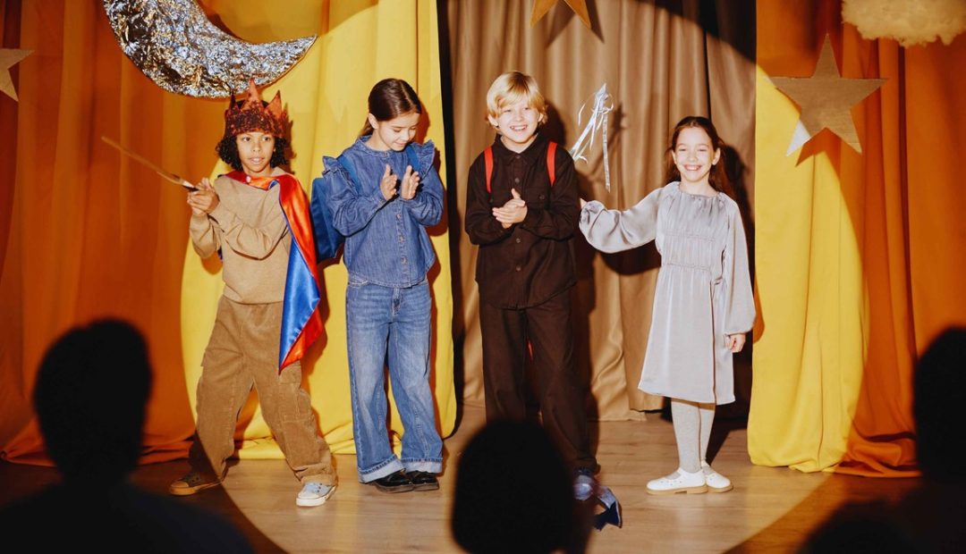 Enfants en costumes colorés jouant sur scène lors d'un spectacle de déguisements