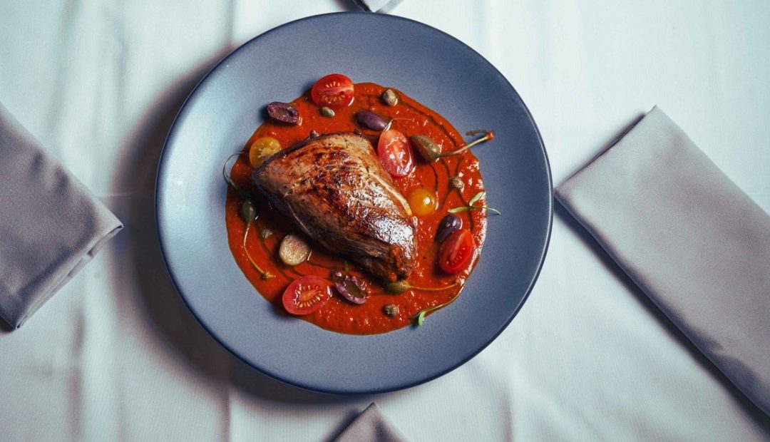 Plat de poulet mijoté en sauce tomate façon basquaise servi dans un plat creux