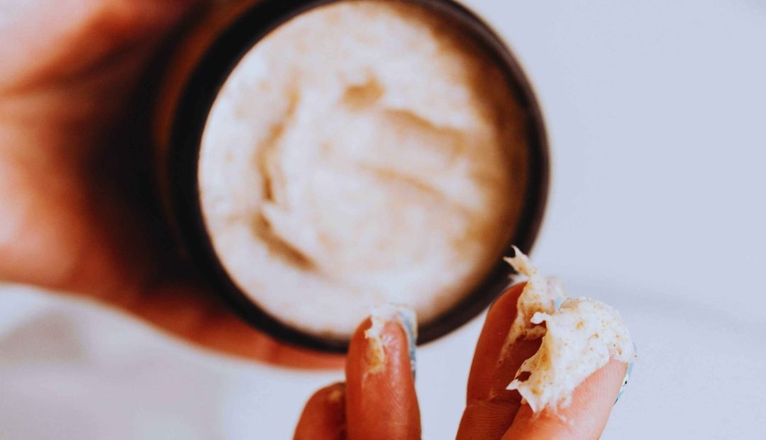 Femme appliquant une crème naturelle sur ses doigts pour hydrater sa peau