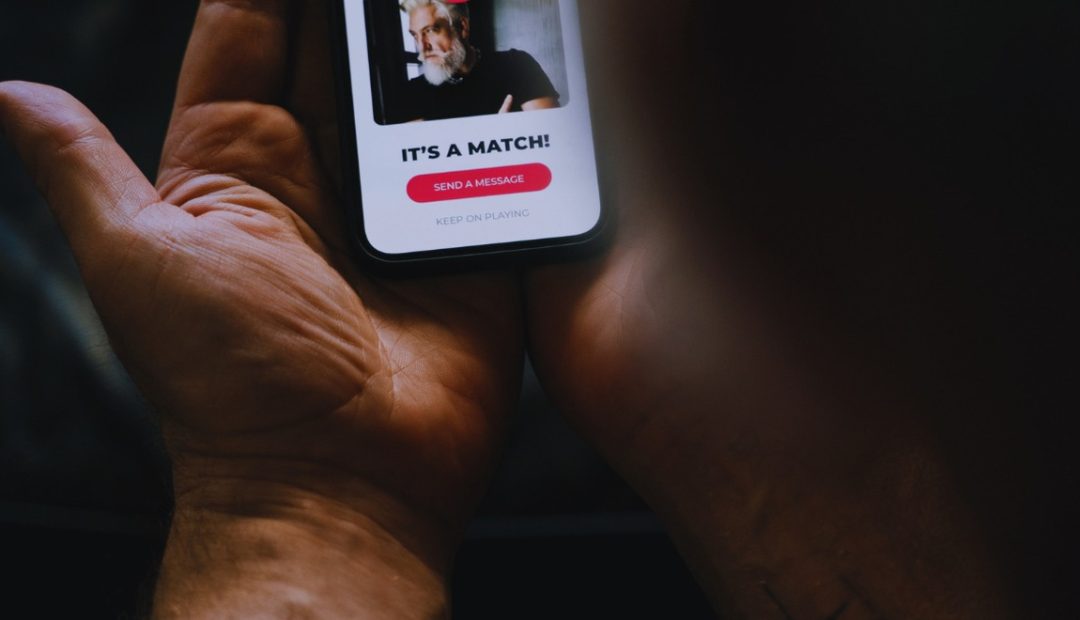 Gros plan sur des mains tenant un smartphone ouvert sur une application de rencontre